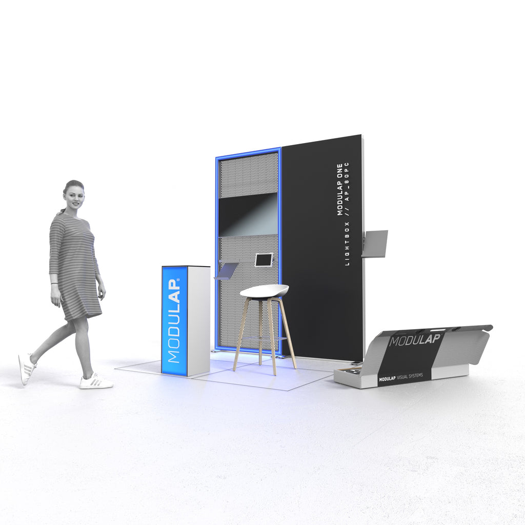Promotionstand mit LED-Leuchtkontur, Texframe und einem schmalen Counter mit dem Schriftzug 'MODULAP' und bietet Platz für Informationsmaterial. Ein Barhocker steht vor dem Counter, während eine Systemverpackung mit MODULAP-Systemen geöffnet ist. Eine Person geht lächelnd am Stand vorbei, der eine moderne und einladende Präsentationsumgebung schafft.