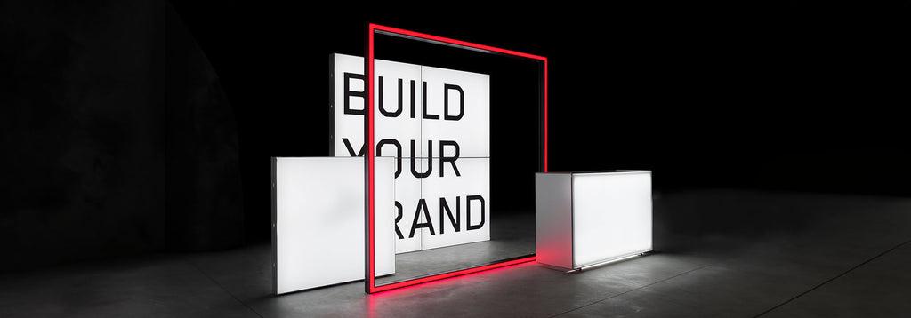 Modularer Messestand mit beleuchtetem Schriftzug 'Build Your Brand' – Stilvolles Design mit leuchtendem roten Rahmen und weißem Counter für markenorientierte Präsentationen.