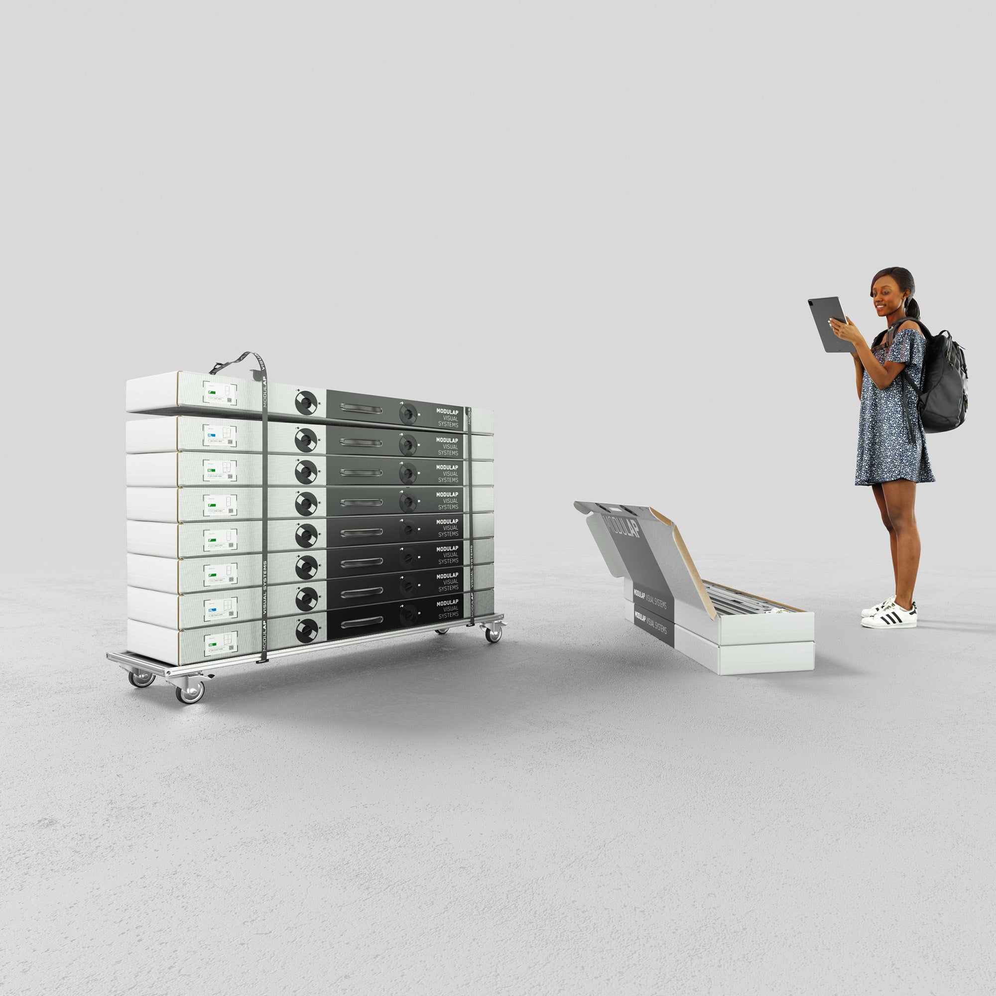  Das Bild zeigt einen Eventstand von Modulap. Links ist ein Rollbrett mit gestapelten Systemverpackungen zu sehen, während rechts eine Frau interessiert auf ein geöffnetes Display-System in einer Systemverpackung blickt. Die Darstellung betont die Mobilität und die einfache Handhabung des Systems.