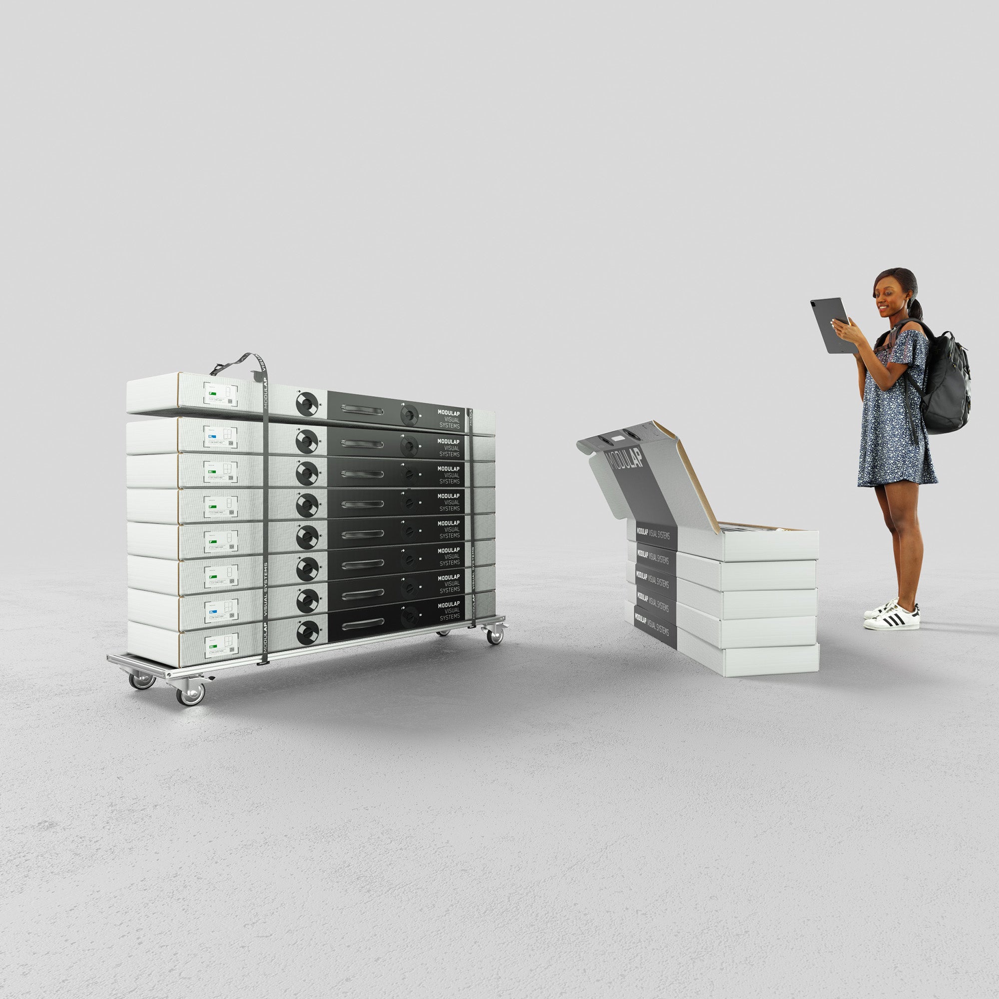 Ein moderner Stand zeigt eine Frau, die mit einem Tablet arbeitet, während sie neben gestapelten Systemverpackungen und einem Rollbrett mit gestapelten Modulen steht. Die Szene verdeutlicht die effiziente und organisierte Verpackung und den Transport von Modulap-Systemen.