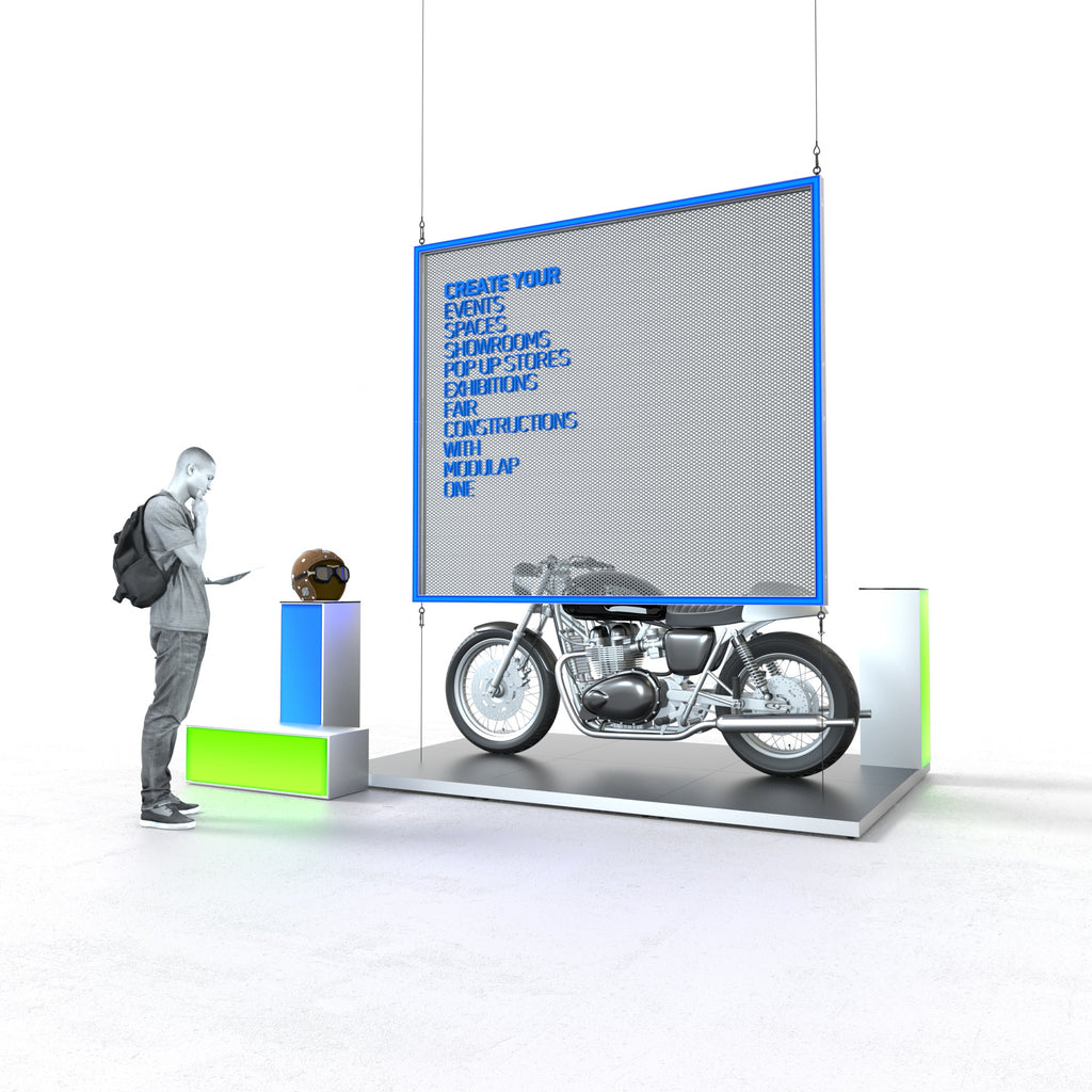 Ein moderner Messestand von Modulap mit einer auffälligen hängenden LED-Leuchtkontur über einer stilvoll präsentierten Motorradplattform. Links steht ein kleiner Counter mit grünen und blauen Akzenten, auf dem ein Helm ausgestellt ist. Ein Besucher mit Rucksack betrachtet den Stand. Der Text auf der Leuchtkontur hebt die vielfältigen Anwendungsmöglichkeiten von Modulap hervor. Der Stand strahlt eine professionelle und einladende Atmosphäre aus.